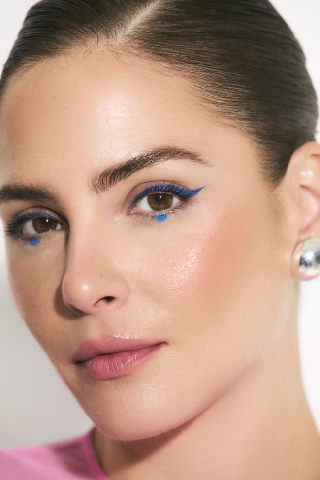 Los pendientes que lleva Andrea son el modelo de plata Daisy de TOUS y el vestido rosa lo firma Juan Vidal. El eyeliner azul se logra con el delineador Diorshow On Stage Liner en tono 181 Satin Indigo y el punto bajo las pestañas, con la sombra de ojos Diorshow Mono Couleur en tono 162 Blue Bayadère. Sobre las mejillas, el sutil brillo del colorete en barra Rosy Glow Stick en tonalidad 103 Toffee. Todo de Dior Belleza.